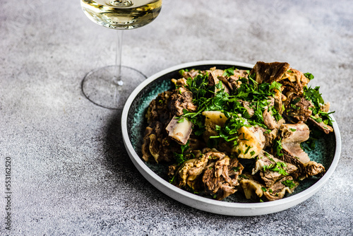 Traditional Georgian boiled meat with coriander and a glass of white wine photo