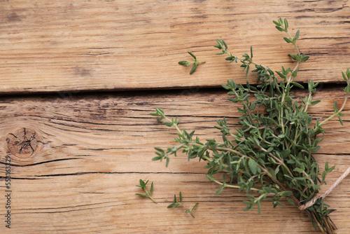 Bunch of fresh thyme on wooden table, top view. Space for text