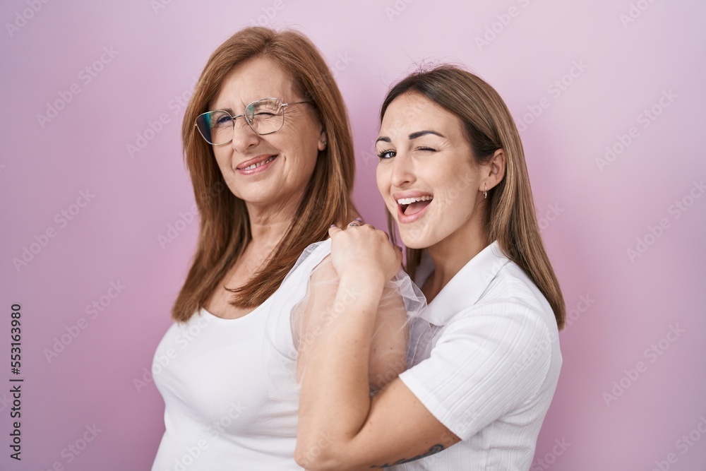 Hispanic mother and daughter wearing casual white t shirt winking looking at the camera with sexy expression, cheerful and happy face. Hispanic mother and daughter wearing casual white t shirt winking looking at the camera with sexy expression, cheerful and happy face.