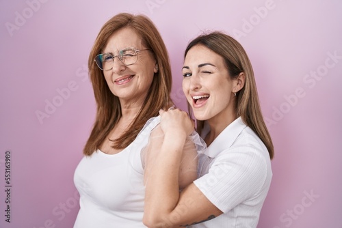 Hispanic mother and daughter wearing casual white t shirt winking looking at the camera with sexy expression, cheerful and happy face.