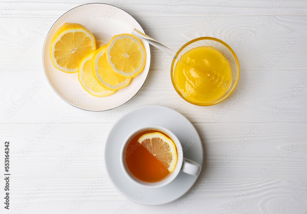 Cup with delicious immunity boosting tea, lemon and honey on white wooden table, flat lay Cup with delicious immunity boosting tea, lemon and honey on white wooden table, flat lay