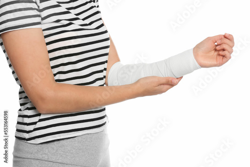Young woman with arm wrapped in medical bandage on white background, closeup