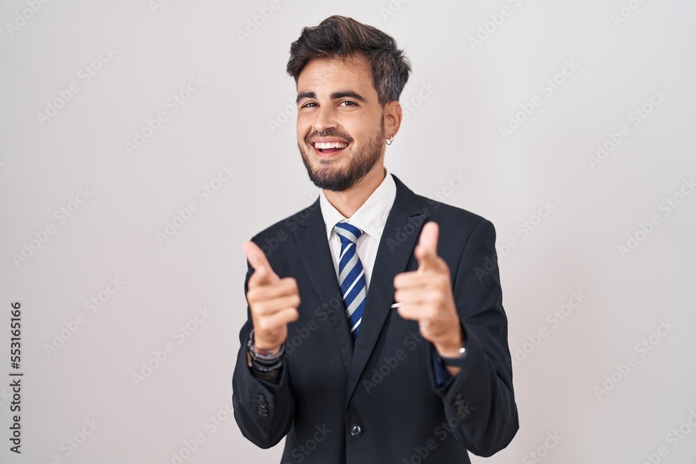 Young hispanic man with tattoos wearing business suit and tie pointing fingers to camera with happy and funny face. good energy and vibes. Young hispanic man with tattoos wearing business suit and tie pointing fingers to camera with happy and funny face. good energy and vibes.