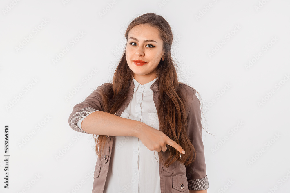 Confident young woman in casual clothes pointing finger down, showing amazing news, promo banner, offer. Portrait of student, secretary, girl, female over white studio background Confident young woman in casual clothes pointing finger down, showing amazing news, promo banner, offer. Portrait of student, secretary, girl, female over white studio background