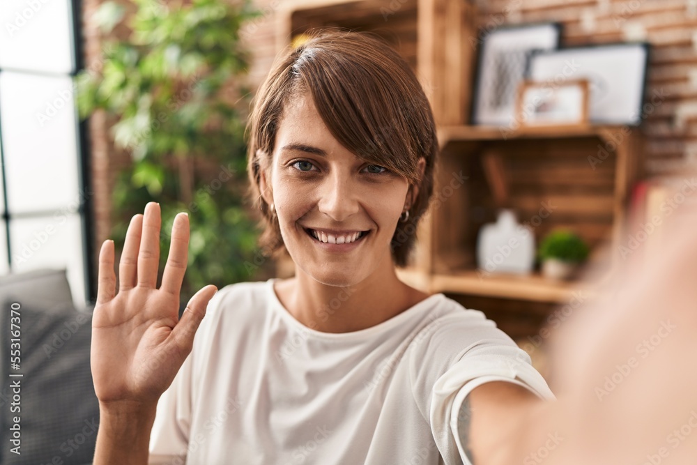 Young beautiful hispanic woman having video call sitting on sofa at home