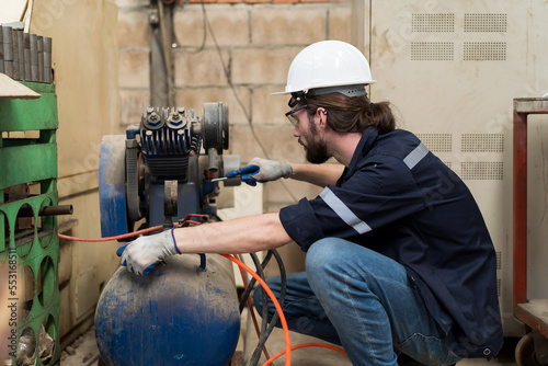 Male engineer worker using air compressor in the industry factory. Male engineer worker checking or maintenance air compressor machine in the factory photo