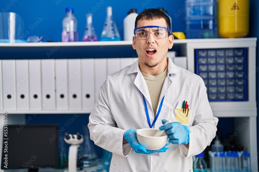 Young arab man working at scientist laboratory angry and mad screaming frustrated and furious, shouting with anger. rage and aggressive concept. Young arab man working at scientist laboratory angry and mad screaming frustrated and furious, shouting with anger. rage and aggressive concept.