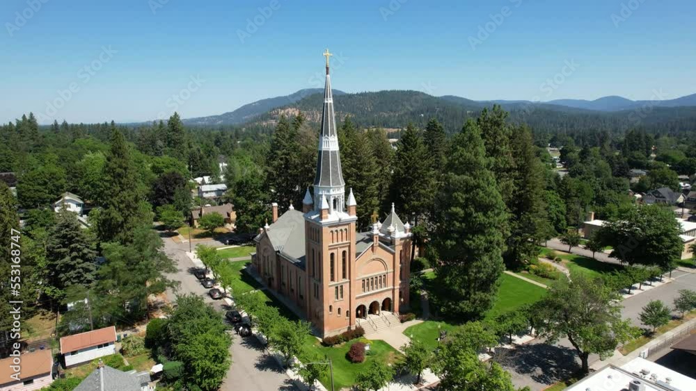 Aerial parallax of a small catholic church cathedral with trees in a neighborhood Aerial parallax of a small catholic church cathedral with trees in a neighborhood