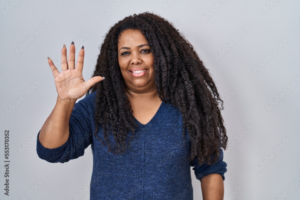 Plus size hispanic woman standing over white background showing and pointing up with fingers number five while smiling confident and happy. Plus size hispanic woman standing over white background showing and pointing up with fingers number five while smiling confident and happy.