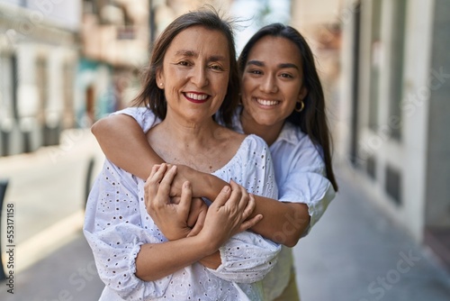 Tableau sur toile Two women mother and daughter smiling confident hugging each other at street
