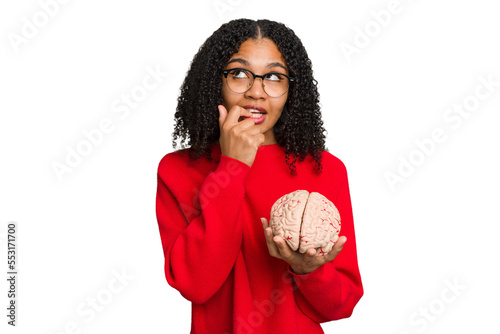 Young african american woman holding a brain model isolated relaxed thinking about something looking at a copy space.