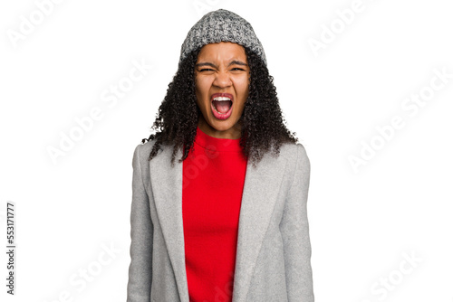 Young african american woman wearing winter jacket isolated screaming very angry and aggressive. © Asier