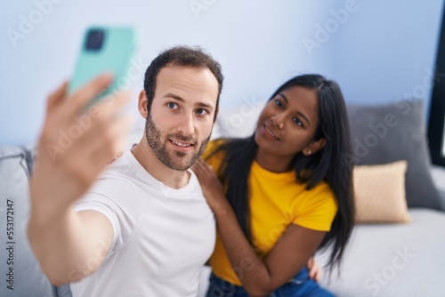 Man and woman interracial couple making selfie by smartphone at home