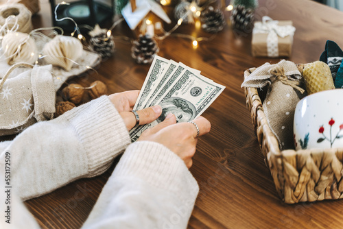 Girl counting US Dollar bills, and planning expenses for Christmas. Woman doing budget, estimating money balance for shopping spree. Female accountant paying taxes. Girl counting Christmas gifts.