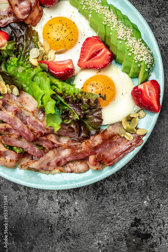Fried egg bacon with avocado, strawberries and fresh salad, Ketogenic, keto or paleo diet, Delicious balanced food concept. place for text, top view