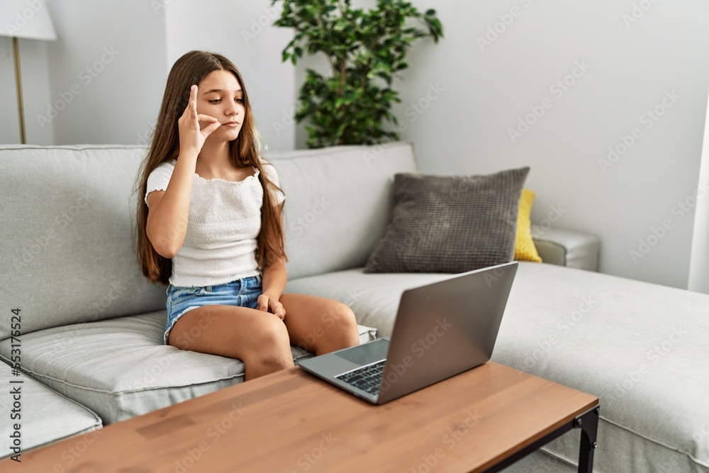 Adorable girl having video call communicating with deaf language sitting on sofa at home Adorable girl having video call communicating with deaf language sitting on sofa at home