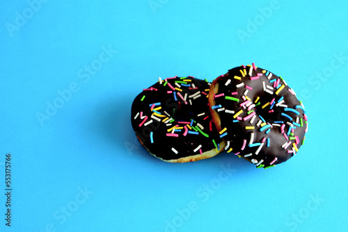 chocolate donuts with multicolored sprinkles isolated on blue background, macro