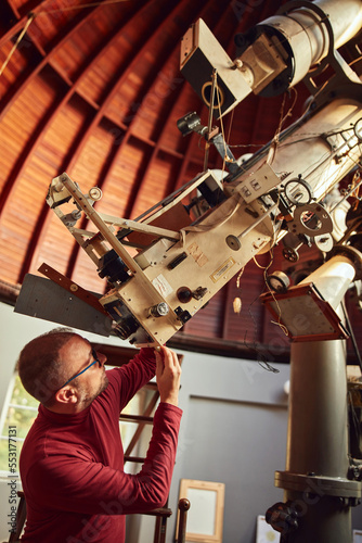 Astronomer with a big astronomical telescope in observatory doing science research.