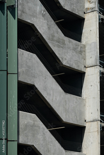 Repeating pattern of the exterior of a multi level parking lot staircase. Abstract pattern of light concrete facade between deep shadow sections. Staircase facade of a multi level car park staircase