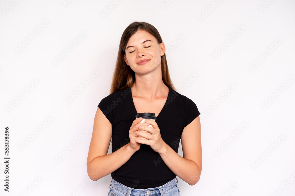 Portrait of happy young woman enjoying takeout coffee. Caucasian lady wearing black T-shirt standing relaxed with closed eyes. Coffee break concept Portrait of happy young woman enjoying takeout coffee. Caucasian lady wearing black T-shirt standing relaxed with closed eyes. Coffee break concept