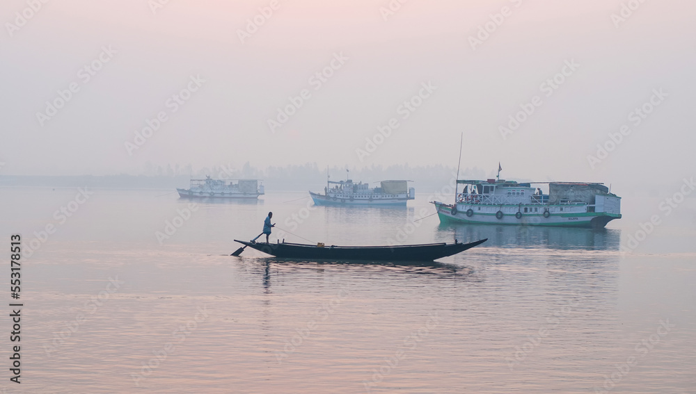 Sundarbans area, West Bengal/India – February 12 2012: Boats in a foggy lagoon at sunrise.