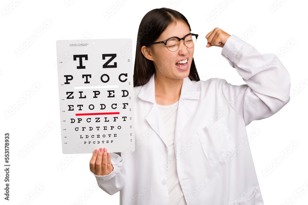 Young asian oculist woman holding a eye chart paper isolated raising fist after a victory, winner concept. Young asian oculist woman holding a eye chart paper isolated raising fist after a victory, winner concept.