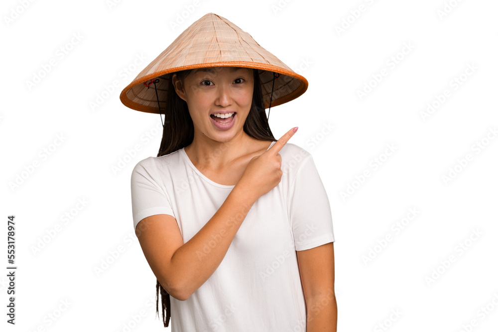 Young asian woman wearing a Vietnamese hat isolated smiling and pointing aside, showing something at blank space. Young asian woman wearing a Vietnamese hat isolated smiling and pointing aside, showing something at blank space.