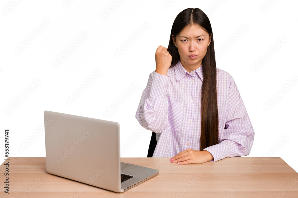 Young student asian woman in a workplace with a laptop isolated showing fist to camera, aggressive facial expression. Young student asian woman in a workplace with a laptop isolated showing fist to camera, aggressive facial expression.