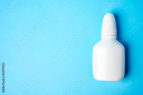 Nasal spray bottle on blue background with copy space