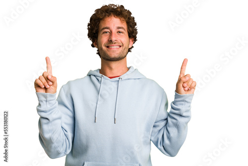 Young curly smart caucasian man cut out isolated indicates with both fore fingers up showing a blank space.