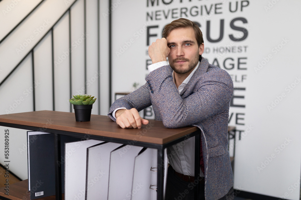 thoughtful businessman stands leaning on a shelf with folders for documents in the office thoughtful businessman stands leaning on a shelf with folders for documents in the office