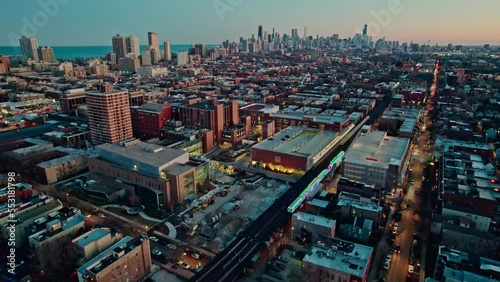 orbiting cta holiday train decorated in chistmas on Brown Lane railroad and tilting up with an epic chicago skyline view at sunset 4k photo