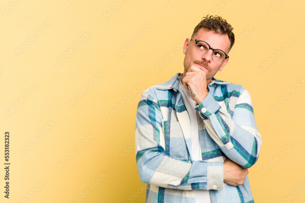 Young caucasian handsome man isolated on yellow background looking sideways with doubtful and skeptical expression. Young caucasian handsome man isolated on yellow background looking sideways with doubtful and skeptical expression.