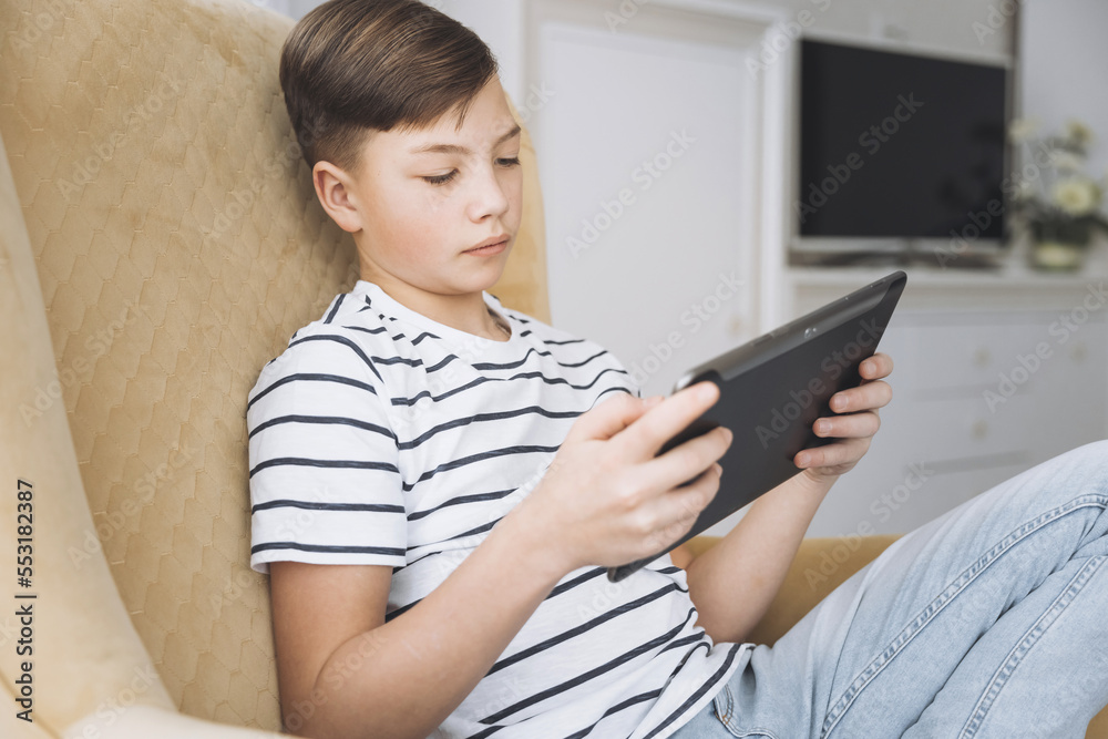 Teenage boy using tablet having video chat on internet online at home. Child watching movie, playing video game. Social media concept. Online education. Distance learning Teenage boy using tablet having video chat on internet online at home. Child watching movie, playing video game. Social media concept. Online education. Distance learning