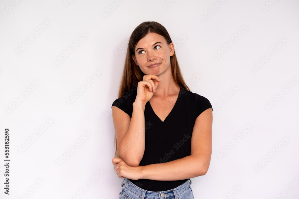 Portrait of thoughtful young woman posing with hand on chin over white background. Caucasian lady wearing black T-shirt looking away and smiling. Dreams and aspirations concept Portrait of thoughtful young woman posing with hand on chin over white background. Caucasian lady wearing black T-shirt looking away and smiling. Dreams and aspirations concept