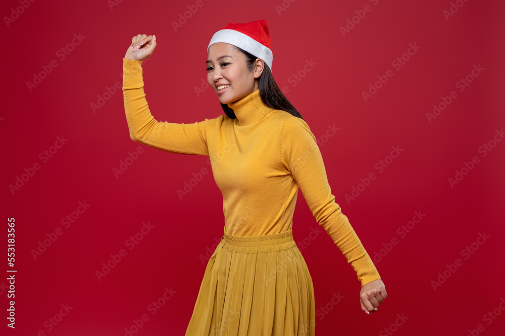 Pretty slim asian woman in yellow dress and santa hat