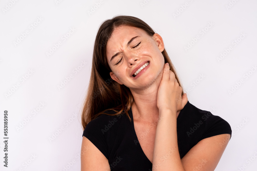 Portrait of frustrated young woman suffering from neck cramp. Caucasian lady wearing black T-shirt touching aching neck over white background. Neck ache concept Portrait of frustrated young woman suffering from neck cramp. Caucasian lady wearing black T-shirt touching aching neck over white background. Neck ache concept