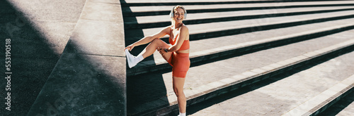 Active and energetic female athlete smiling while stretching, exercising, listening to music and enjoying a healthy lifestyle
