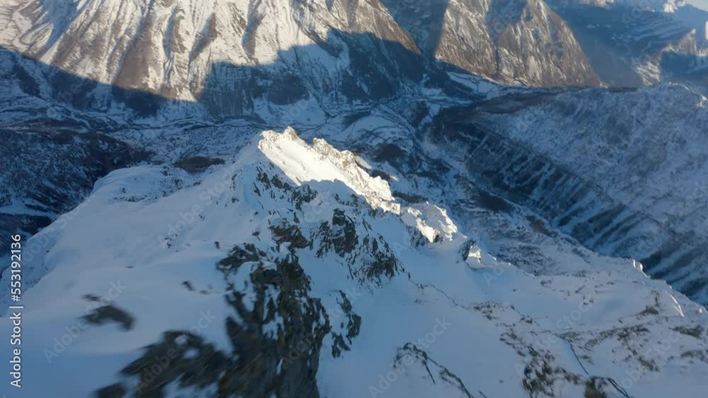 Dizzying descent in a FPV drone along a high snowy mountain cliff in the Hautes Alpes