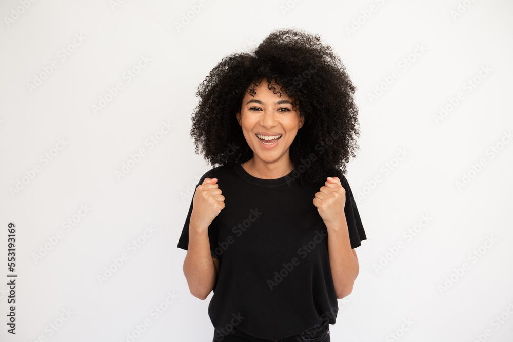 Cheerful young woman in boxing pose. Caucasian female model with afro hairstyle and brown eyes in casual clothes smiling, demonstrating her fists strength. Sport, vitality concept Cheerful young woman in boxing pose. Caucasian female model with afro hairstyle and brown eyes in casual clothes smiling, demonstrating her fists strength. Sport, vitality concept