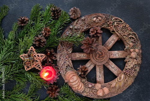 wiccan altar with Wheel of the year candle, amulet deer, cones, fir branches on dark abstract background. Witchcraft Esoteric Ritual. symbol of Yule, Winter Solstice holiday. top view