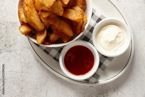 Close up of bowl of wedges with sweet chilli and sour cream on the side photo