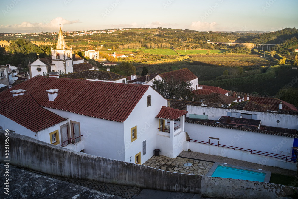Narrow cobblestone streets, historic white houses covered with ceramic tiles, townhouses and the castle of the town of Obidos.