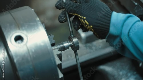 A man working on a lathe in a workshop cutting threads into parts