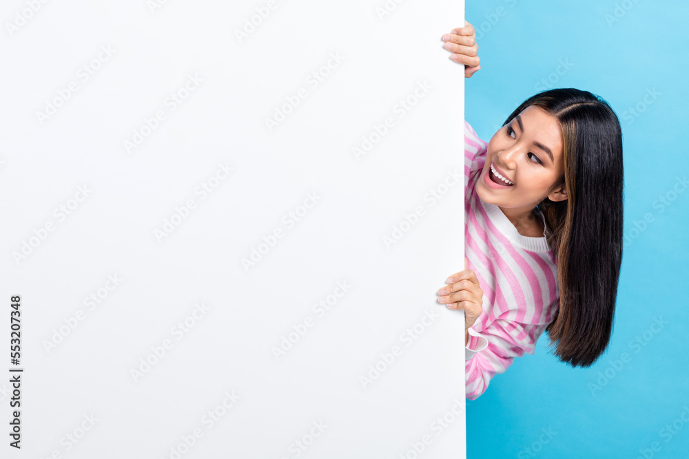 Photo of cute young vietnamese gorgeous lady hide behind huge banner presentation look interested empty space isolated on blue color background Photo of cute young vietnamese gorgeous lady hide behind huge banner presentation look interested empty space isolated on blue color background