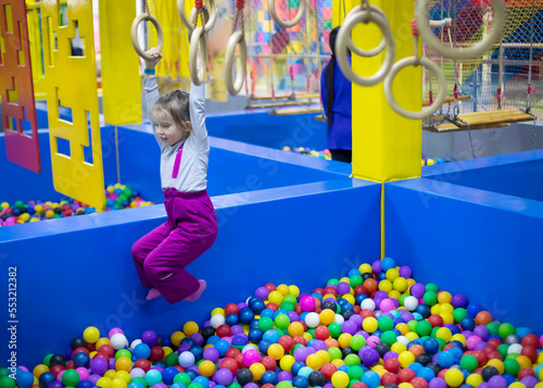 Little cute toddler girl play with gymnastic rings in children playcenter. Toddler girl in Day Care Play Room