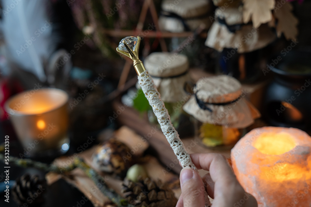 Obraz premium Witch hand holds magic wand. Magic items scene. Witchcraft objects background.