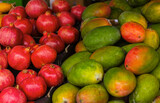 close up mangoes and pomegranates on counter in store. textured background of natural fruits