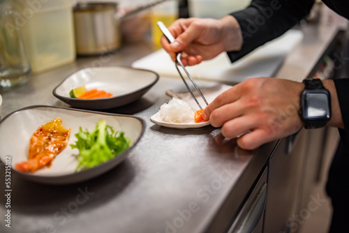 chef cooking slice salmon fish and shrimp with salad on kitchen