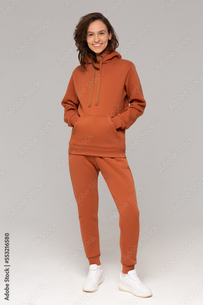 Smiling woman with thick curly hair in a brown suit of hoodies and sweatpants. Mock-up.
